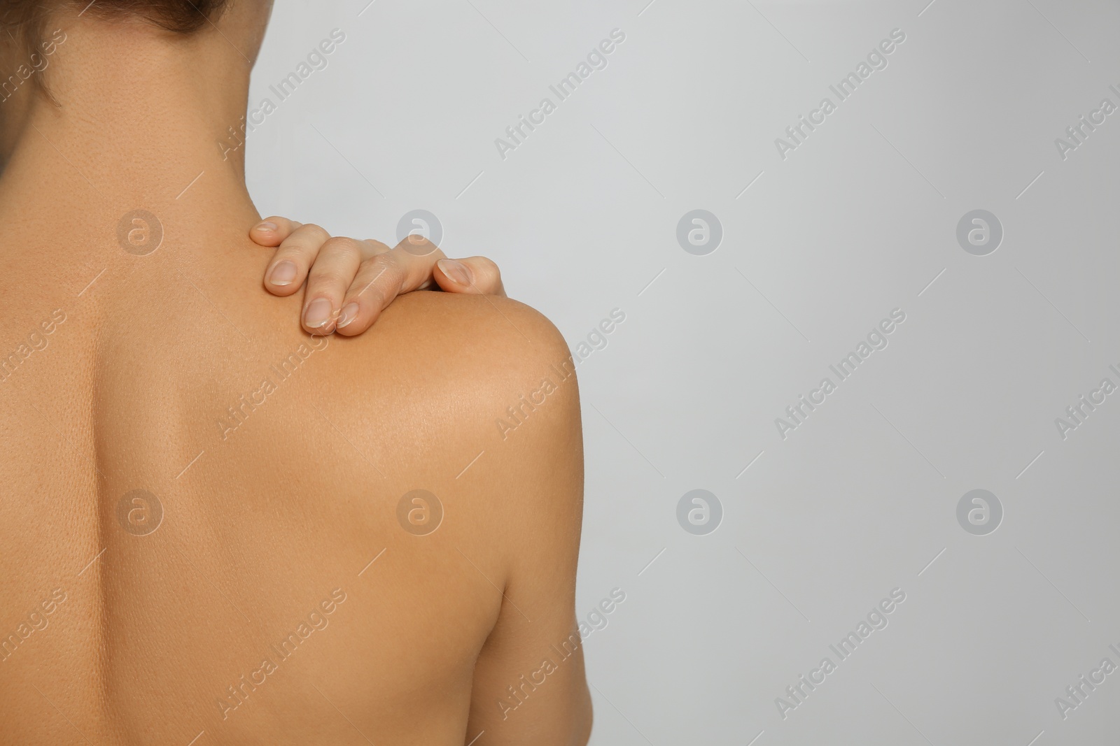 Photo of Back view of woman with perfect smooth skin on light grey background, space for text. Beauty and body care