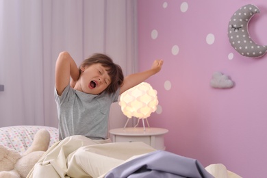 Photo of Little girl yawning on bed at home. Time to sleep