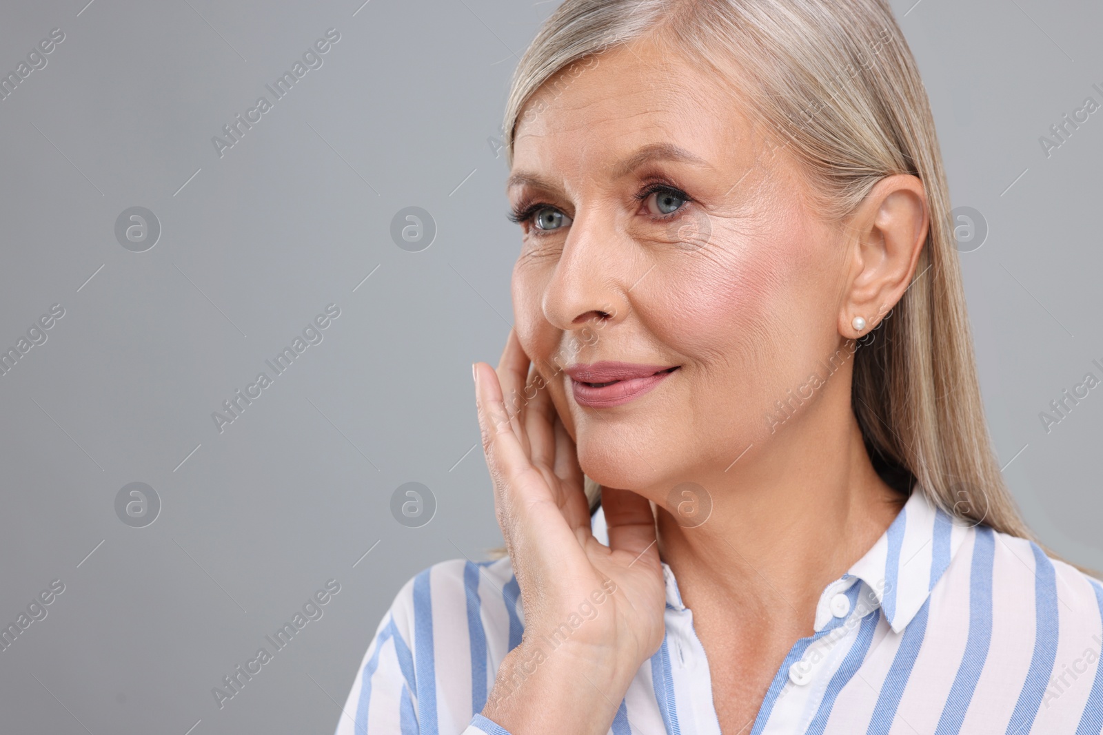 Photo of Portrait of beautiful middle aged woman on light grey background. Space for text