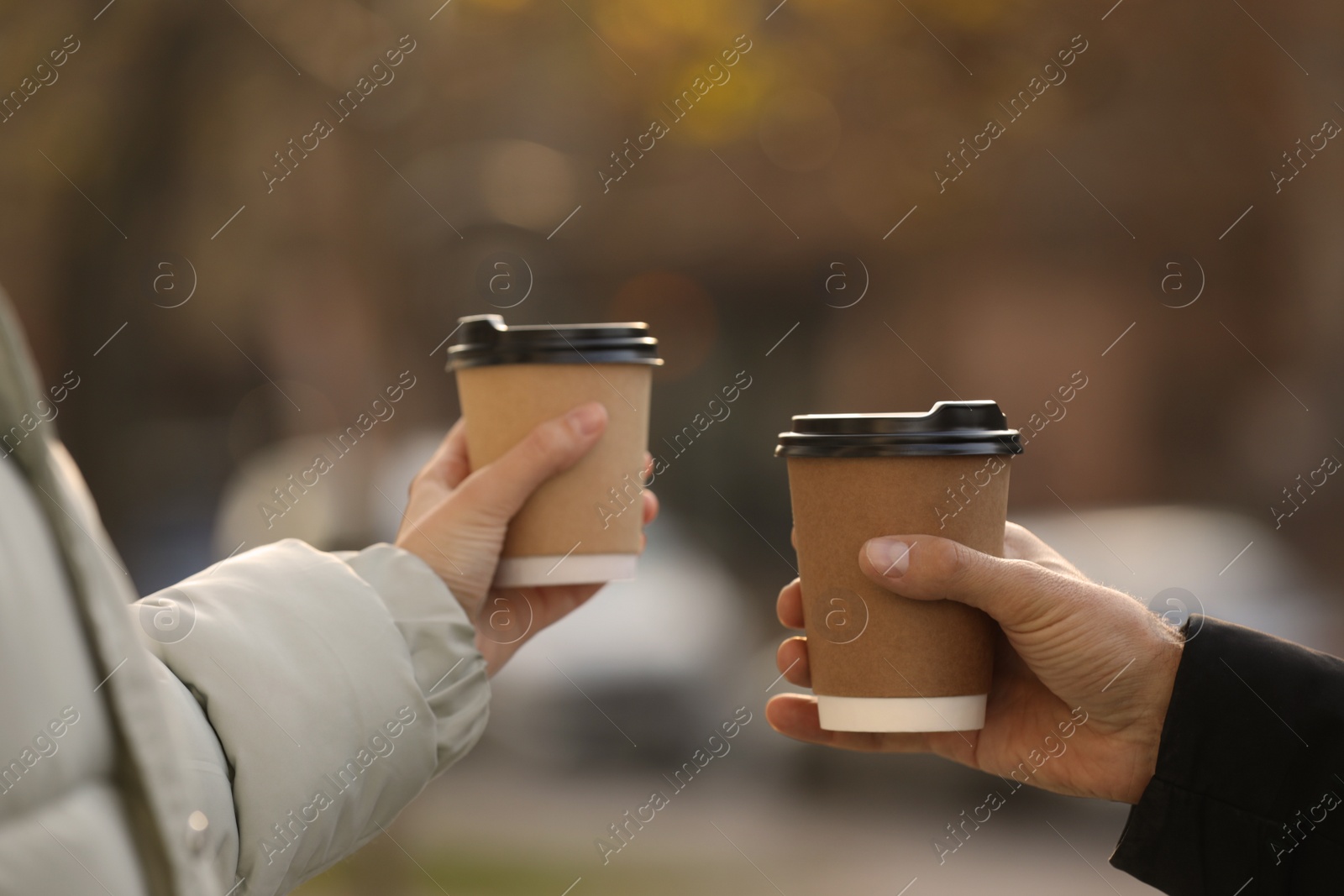 Photo of Couple with takeaway coffee cups outdoors, closeup