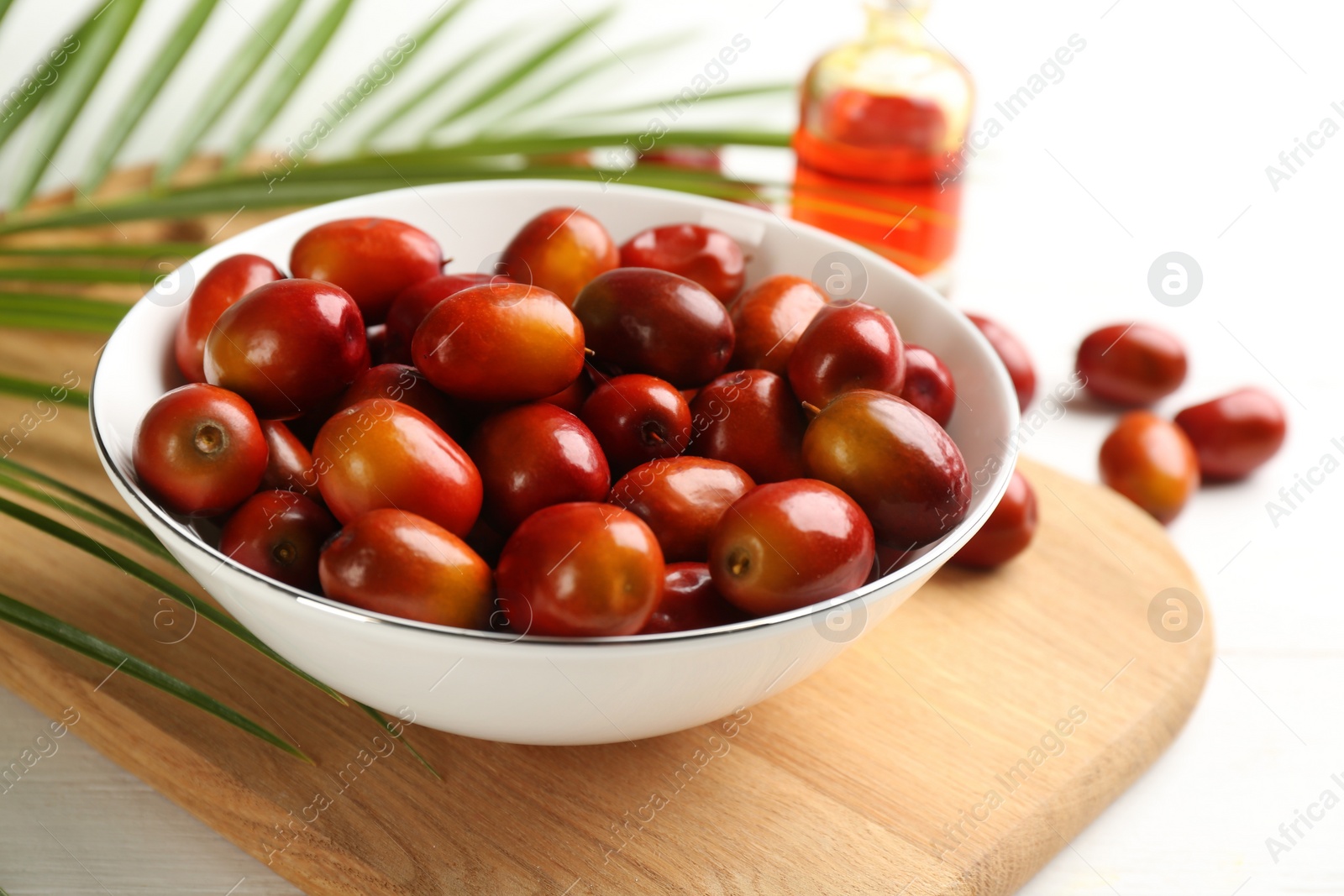 Photo of Palm oil fruits in bowl on white table, closeup