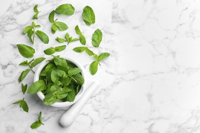 Fresh mint with mortar and pestle on white marble background, flat lay. Space for text