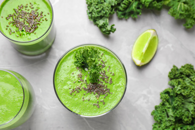 Photo of Tasty kale smoothie on light grey marble table, flat lay