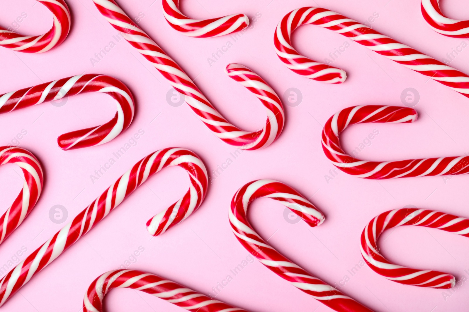 Photo of Sweet Christmas candy canes on pink background, flat lay