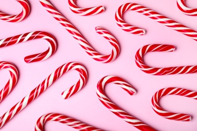 Sweet Christmas candy canes on pink background, flat lay