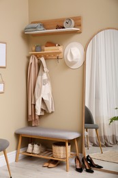 Photo of Hallway interior with stylish furniture, accessories and wooden hanger for keys on beige wall