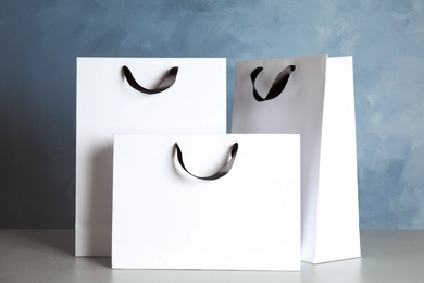 Photo of Paper shopping bags on table against color background. Mock up for design