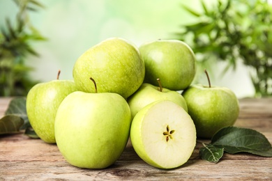 Pile of fresh ripe green apples on wooden table against blurred background