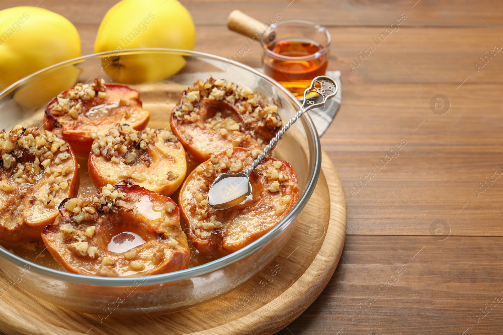 Photo of Tasty baked quinces with walnuts and honey in bowl on wooden table, closeup. Space for text