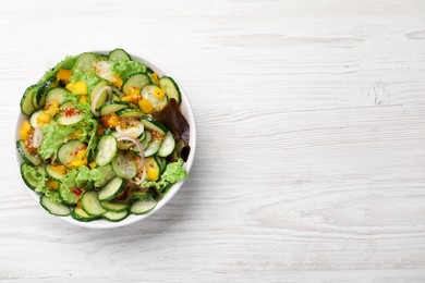 Bowl of delicious cucumber salad on white wooden table, top view. Space for text