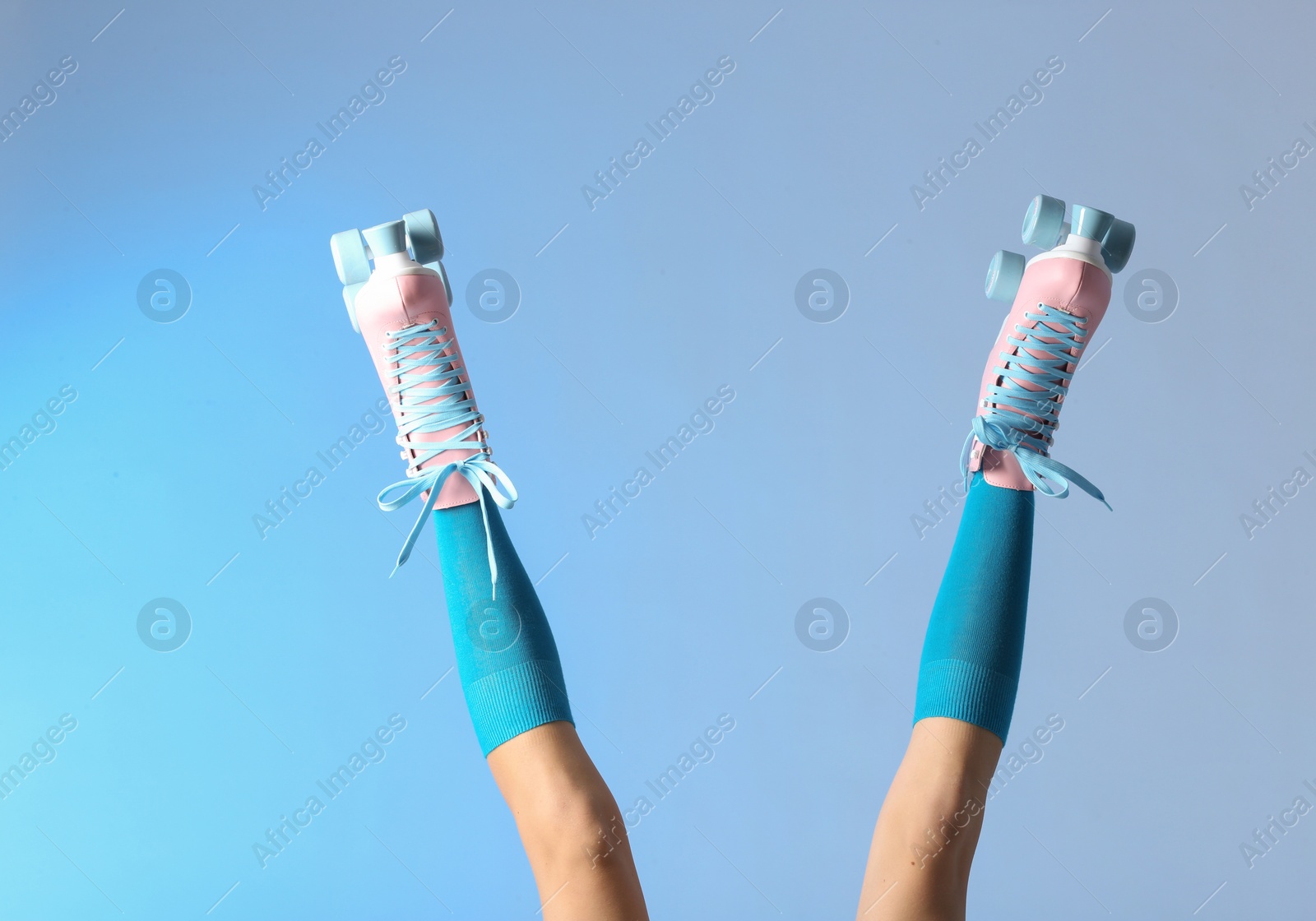 Photo of Woman with vintage roller skates on color background, closeup