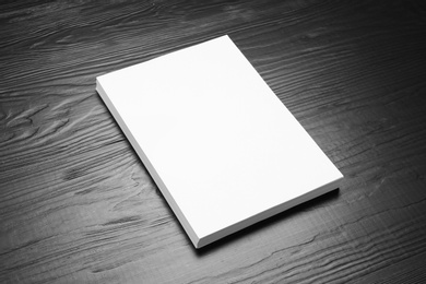 Photo of Stack of blank paper sheets for brochure on black wooden background. Mock up