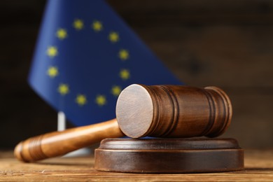 Photo of Judge's gavel and European Union flag on wooden table, closeup