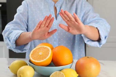 Photo of Woman suffering from food allergies refusing eat citrus fruits at table indoors, closeup