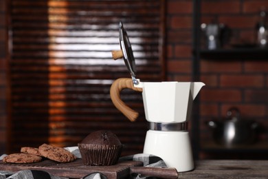 Photo of Brewing coffee. Moka pot, cookies and muffin on wooden table, closeup