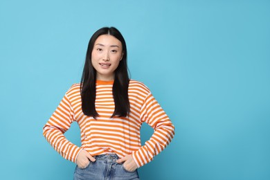 Portrait of happy woman on light blue background. Space for text