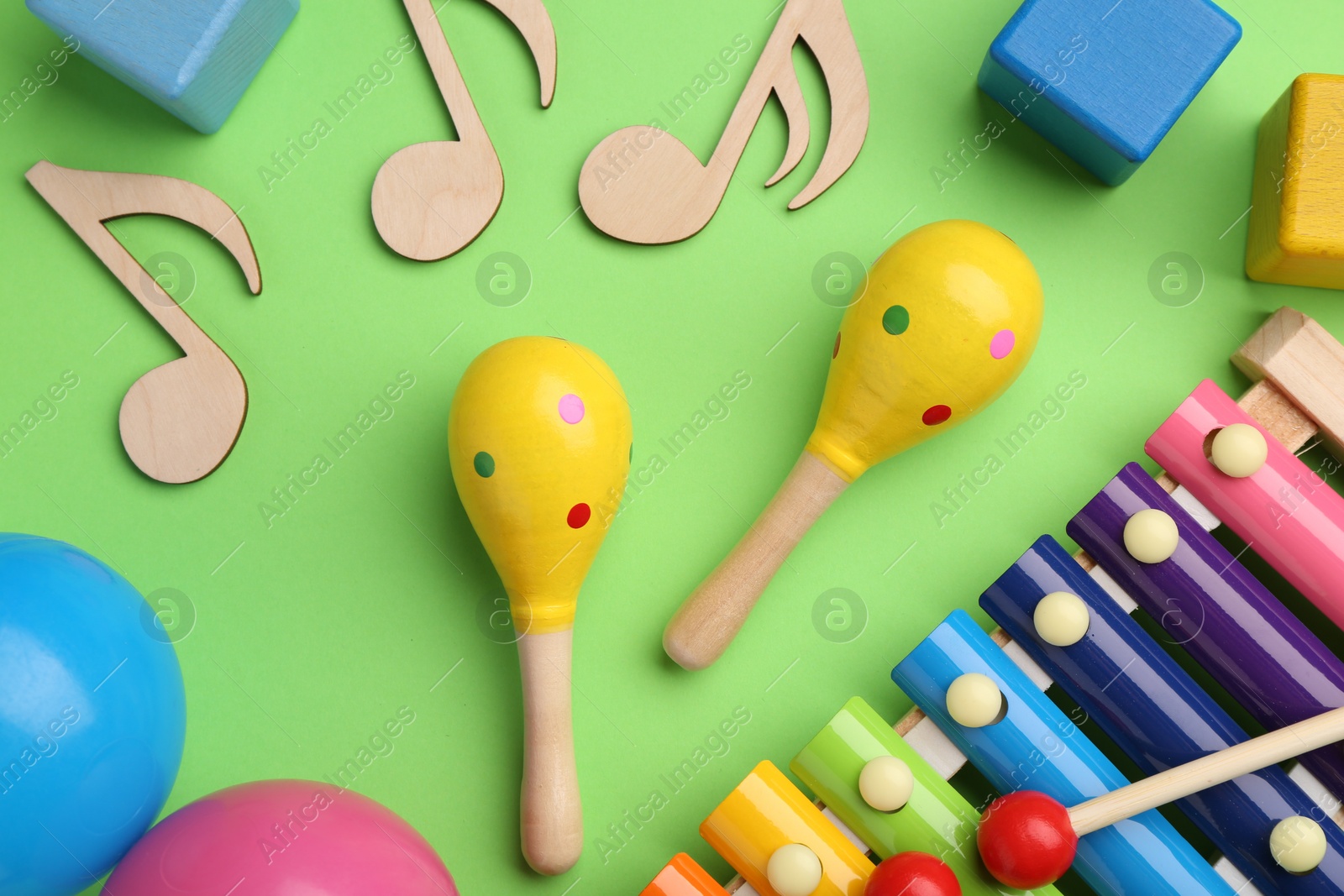 Photo of Tools for creating baby songs. Flat lay composition with maracas on green background