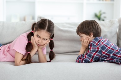 Upset brother and sister on sofa at home