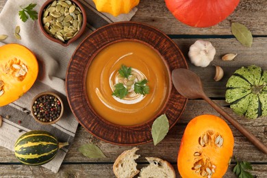 Photo of Flat lay composition with bowl of delicious pumpkin soup on wooden table