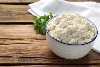 Photo of Delicious fresh cottage cheese with parsley on wooden table, closeup. Space for text