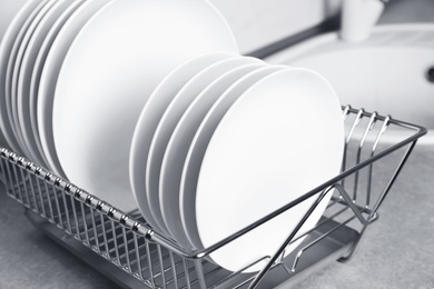 Photo of Drying rack with clean dishes on kitchen counter