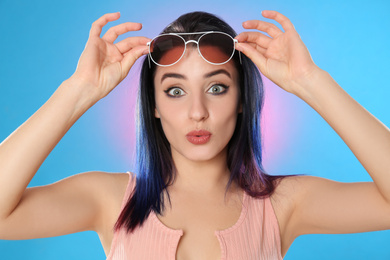 Emotional young woman with bright dyed hair on color background