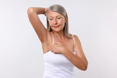 Photo of Beautiful senior woman doing breast self-examination on white background