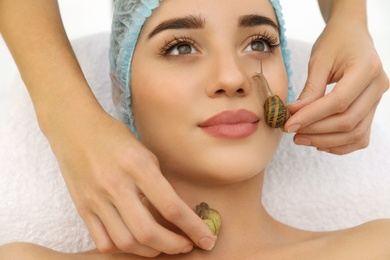 Young woman receiving snail facial massage in spa salon, closeup