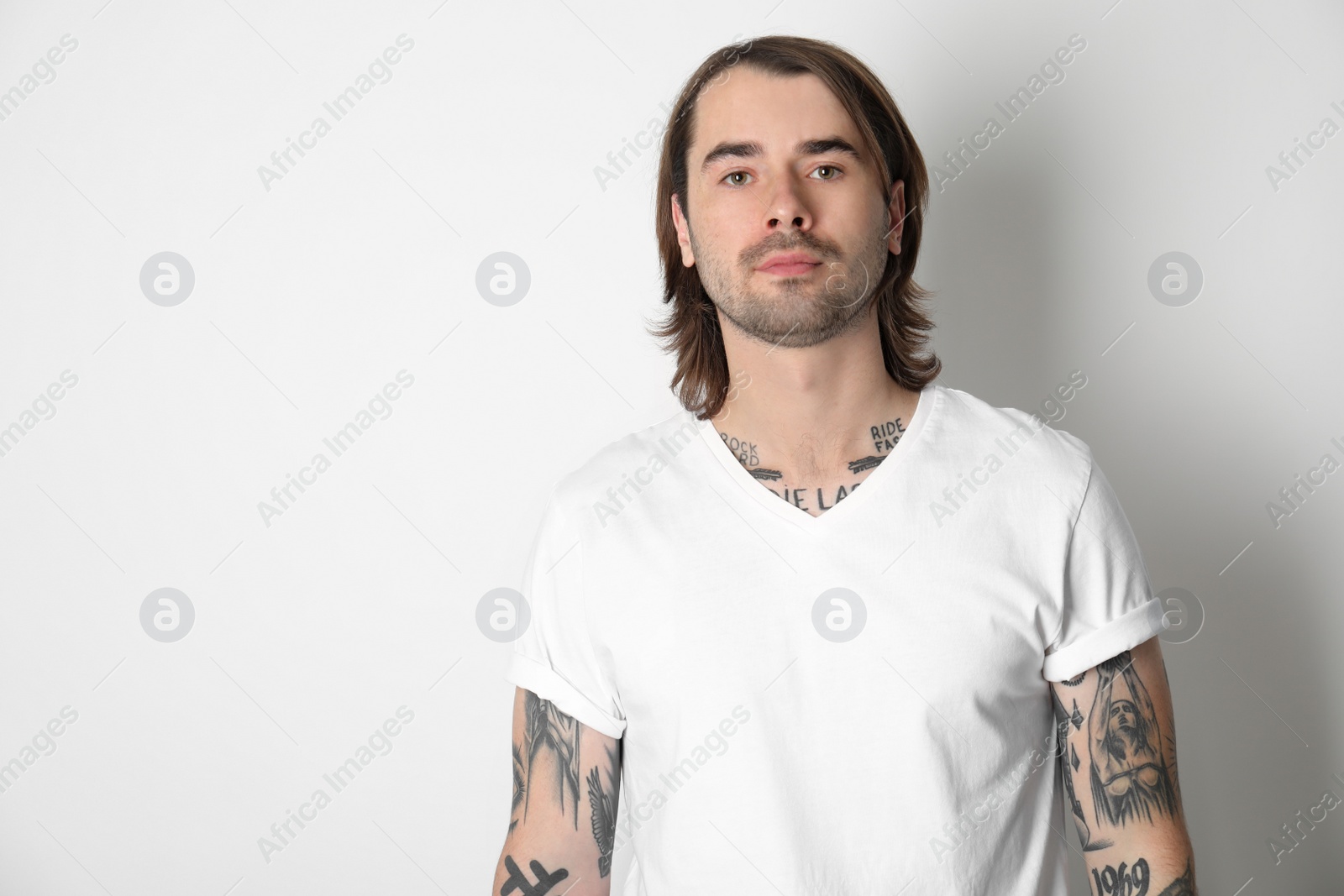 Photo of Young man with tattoos on arms against white background