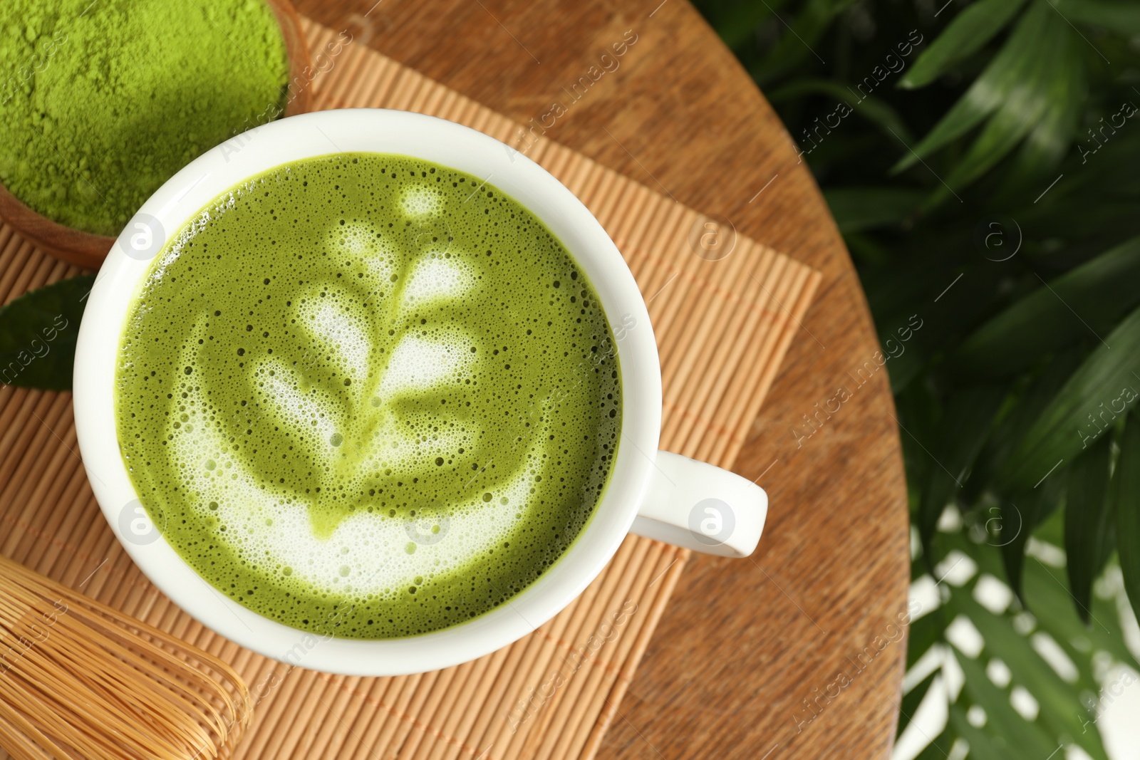 Photo of Delicious matcha latte in cup and powder on wooden coffee table, flat lay