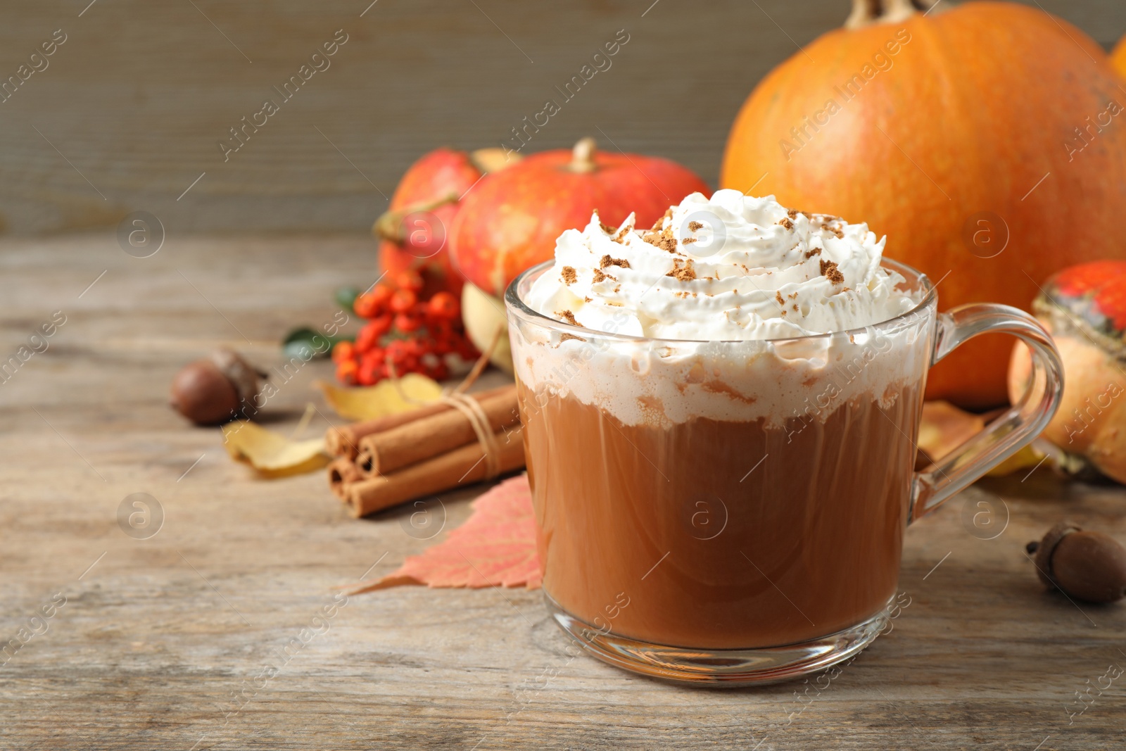 Photo of Glass cup with tasty pumpkin spice latte on wooden table, space for text