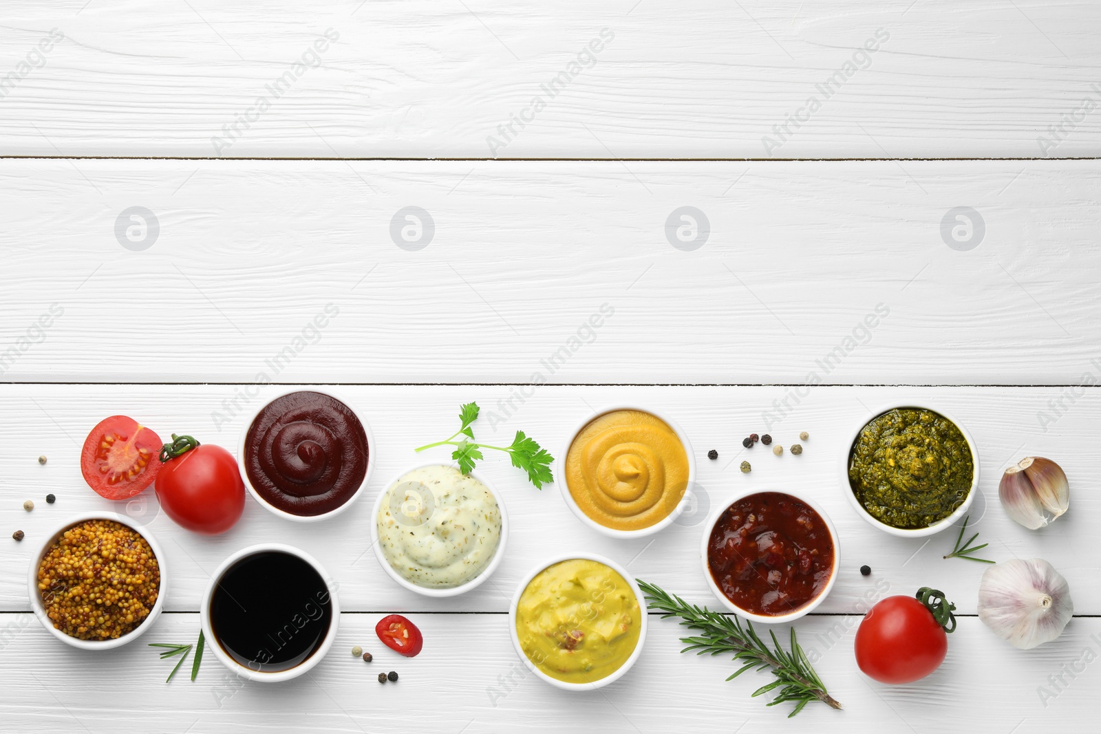 Photo of Many different sauces, spices and vegetables on white wooden table, flat lay. Space for text