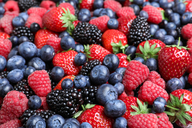 Photo of Mix of different ripe tasty berries as background, closeup view