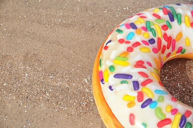 Photo of Bright inflatable doughnut ring on sandy beach. Space for text