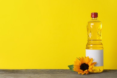 Bottle of cooking oil, sunflower and seeds on wooden table, space for text