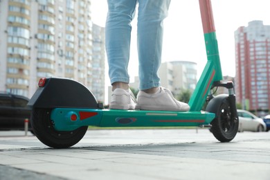 Photo of Man riding modern electric kick scooter on city street, closeup