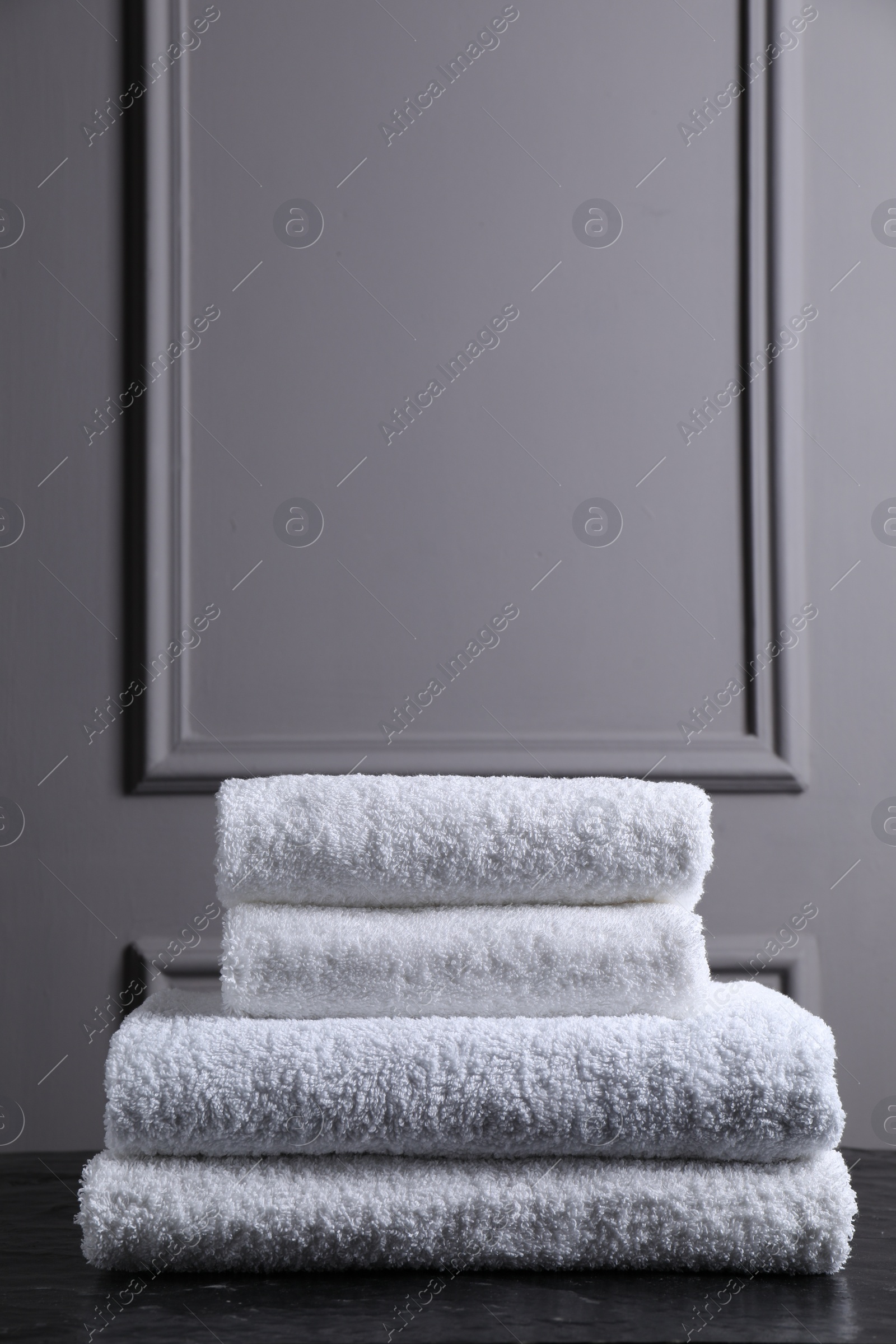 Photo of Stacked terry towels on black textured table indoors, space for text