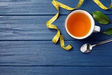 Photo of Flat lay composition with herbal diet tea and measuring tape on blue wooden table, space for text. Weight loss concept