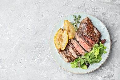 Photo of Pieces of delicious roasted beef meat, caramelized pear and greens on light textured table, top view. Space for text