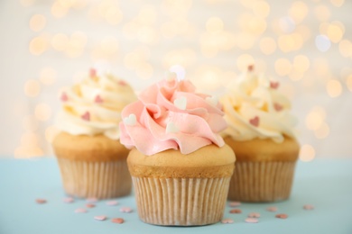 Tasty cupcakes for Valentine's Day on table against blurred lights