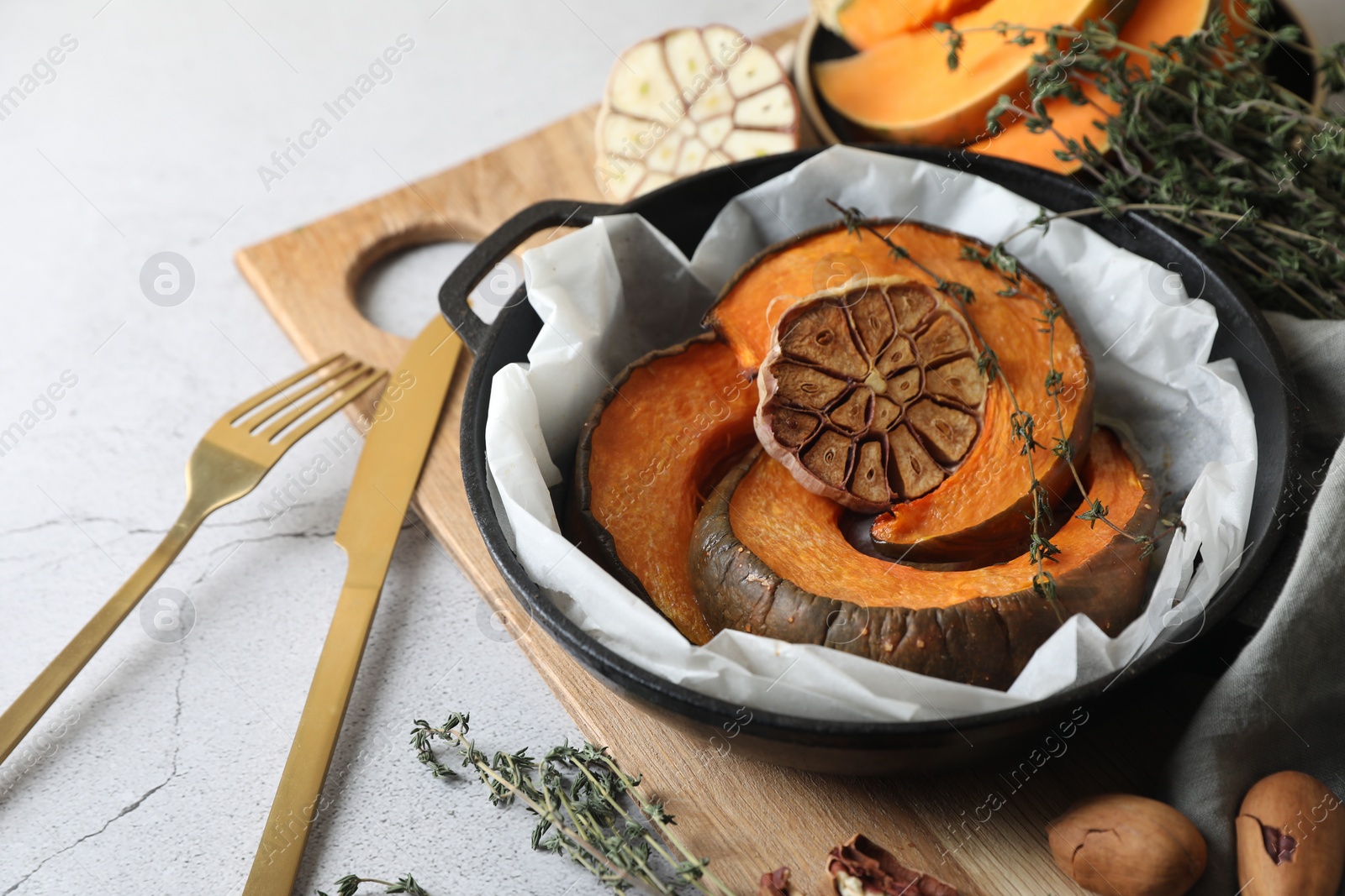 Photo of Freshly baked pumpkin slices with garlic and thyme on light table, closeup