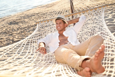 Photo of Man relaxing in hammock on beach. Summer vacation