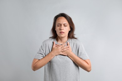 Photo of Mature woman suffering from breathing problem on light background