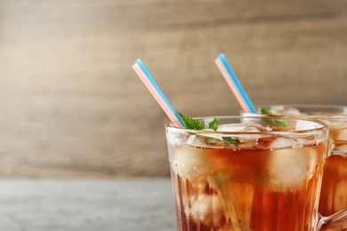 Photo of Cups of refreshing iced tea against wooden background, closeup. Space for text