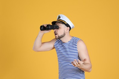 Photo of Sailor looking through binoculars on yellow background