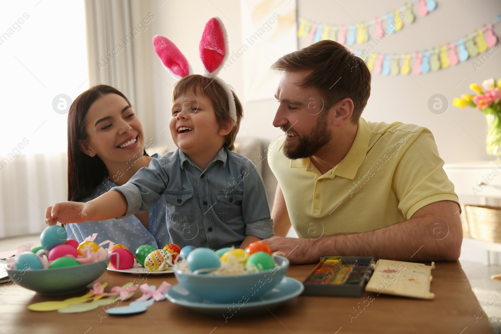 Photo of Happy family painting Easter eggs at table indoors