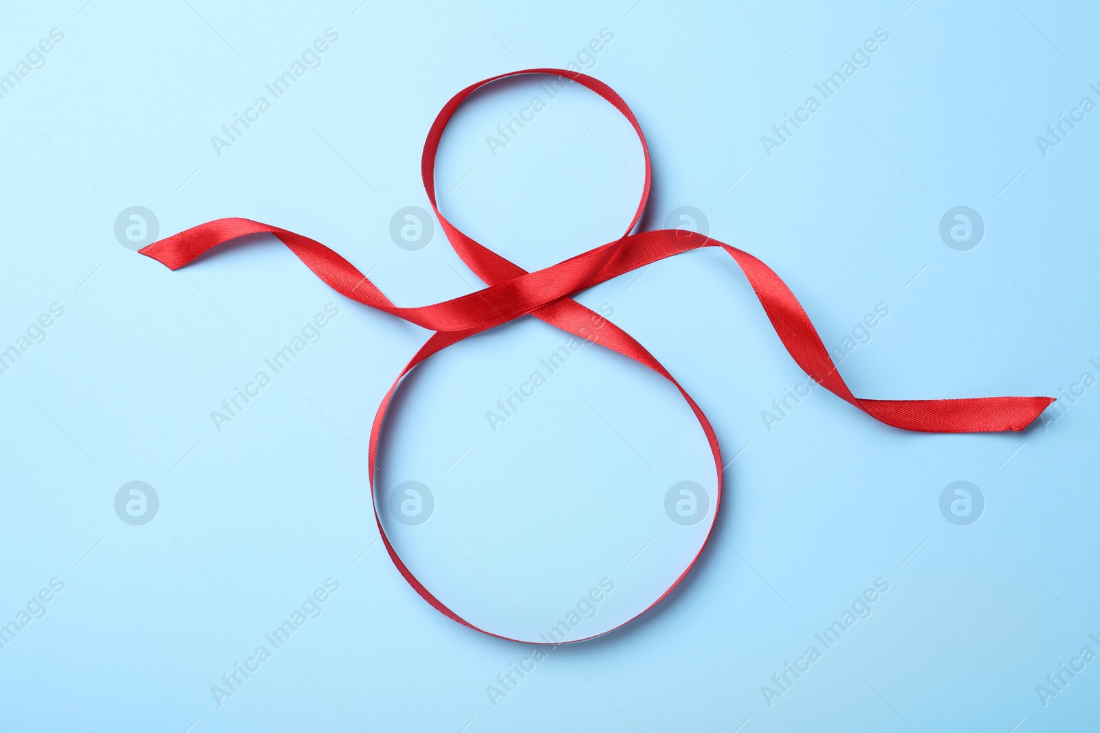 Photo of Number 8 of red ribbon on light blue background, top view. International Women's day