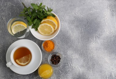 Cup with delicious immunity boosting tea and ingredients on grey table, flat lay. Space for text