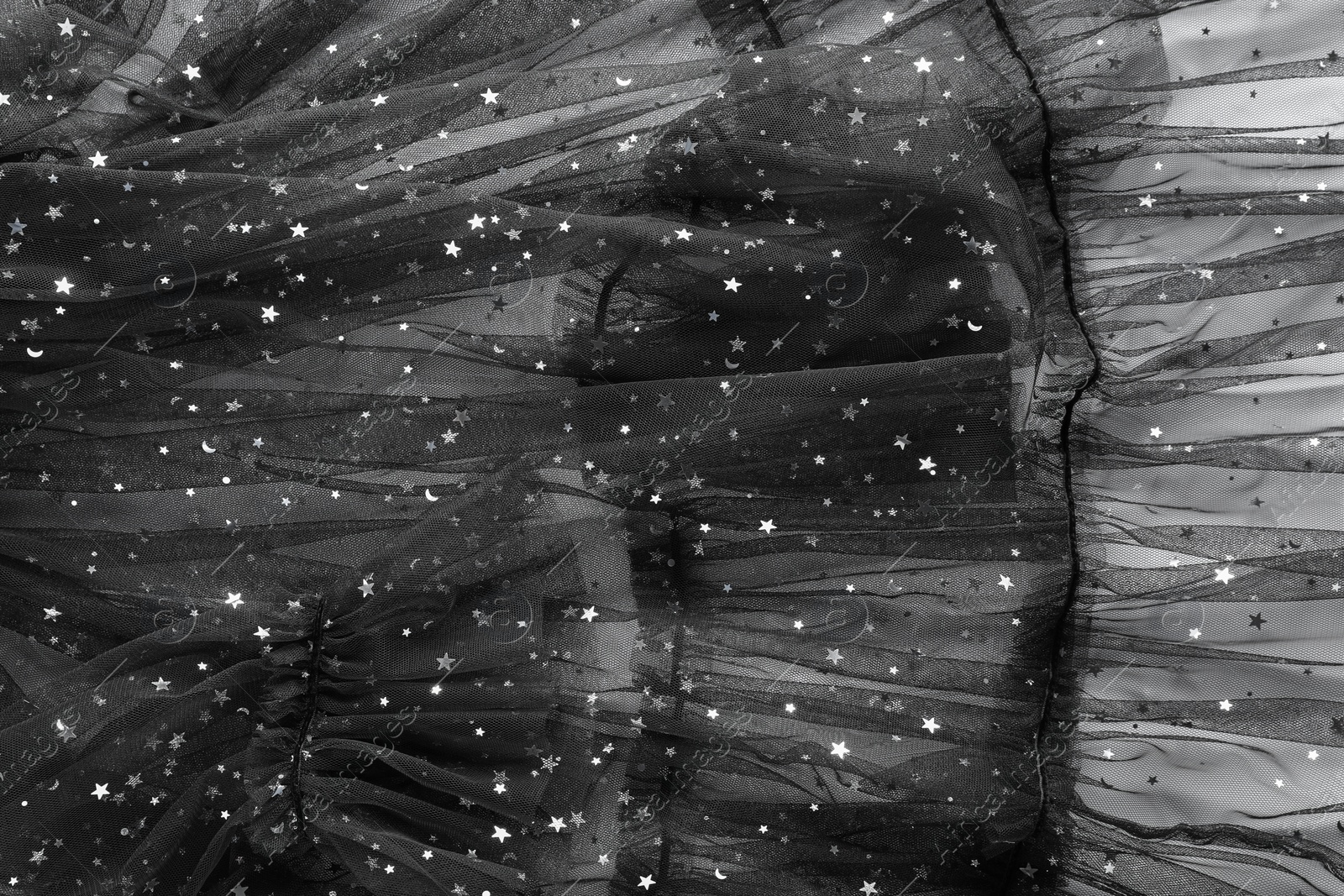 Photo of Beautiful black tulle fabric with shiny stars as background, top view