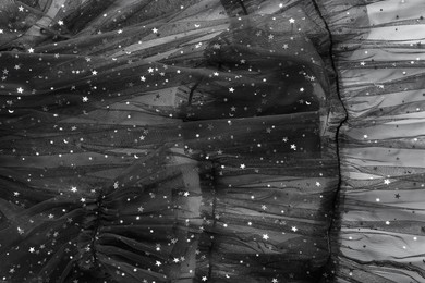 Beautiful black tulle fabric with shiny stars as background, top view